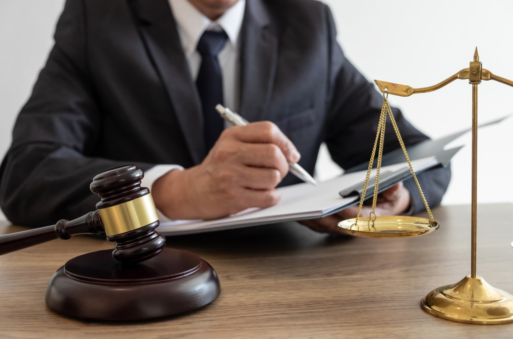 Ręka wskazująca na paragrafy prawne w książce, symbolizująca doradztwo prawne w zakresie importu samochodów.